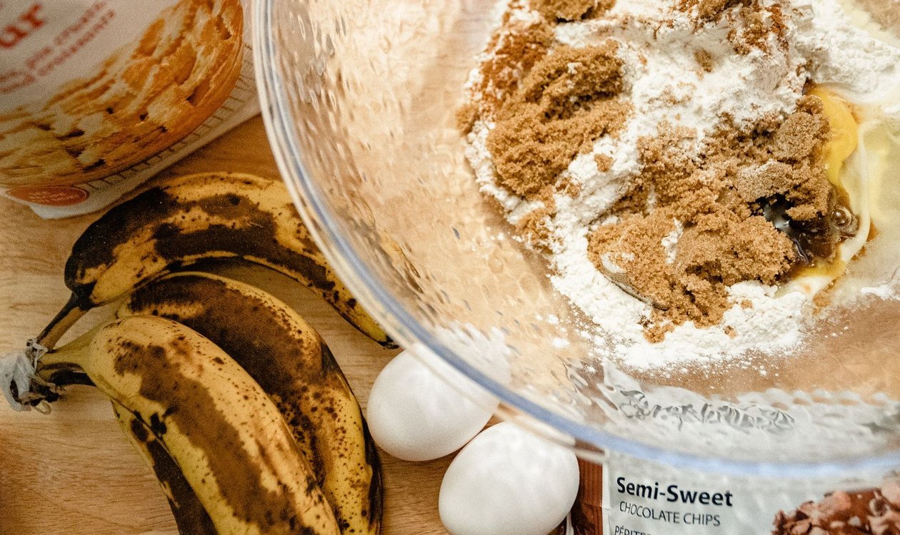 Ripe bananas, flour and eggs laid out as banana bread ingredients