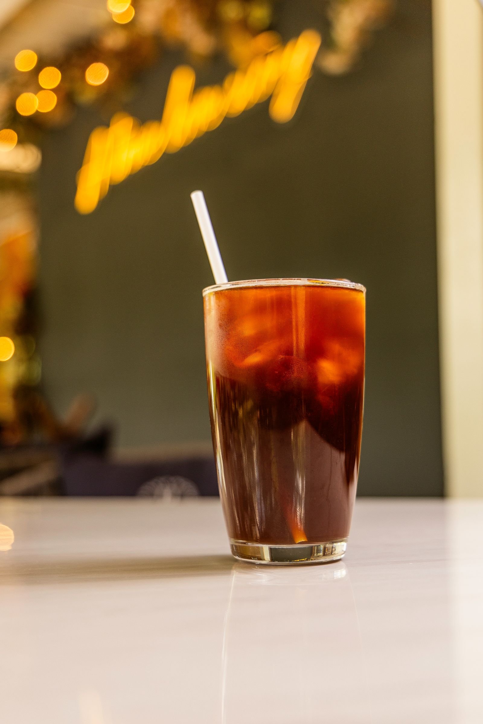 Tall glass of iced cold brew coffee with a straw