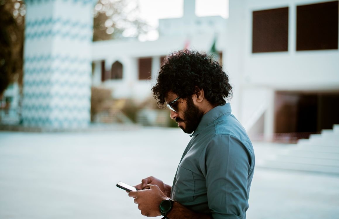 Person holding an iPhone showing the home screen with app icons