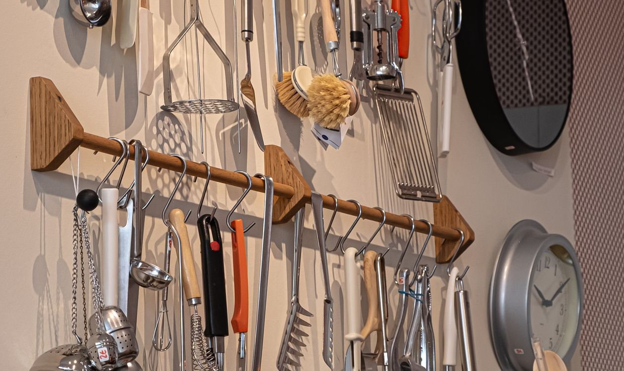 Kitchen utensils hanging neatly on a wall rail in a small kitchen