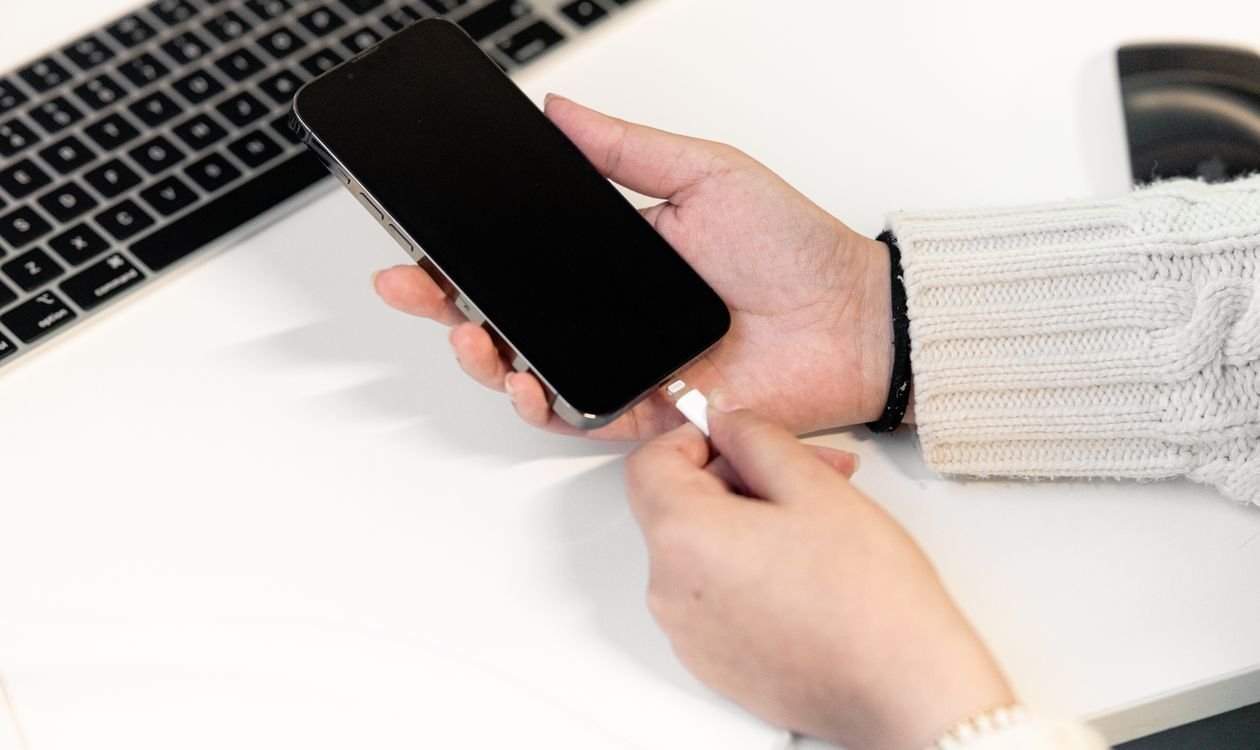 Person plugging an iPhone into a charger at home