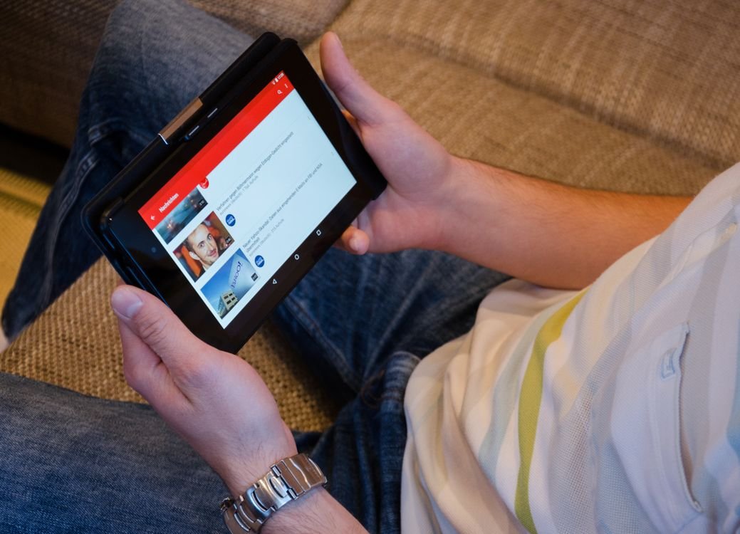 Person holding a tablet showing a streaming app to pick Halloween movies