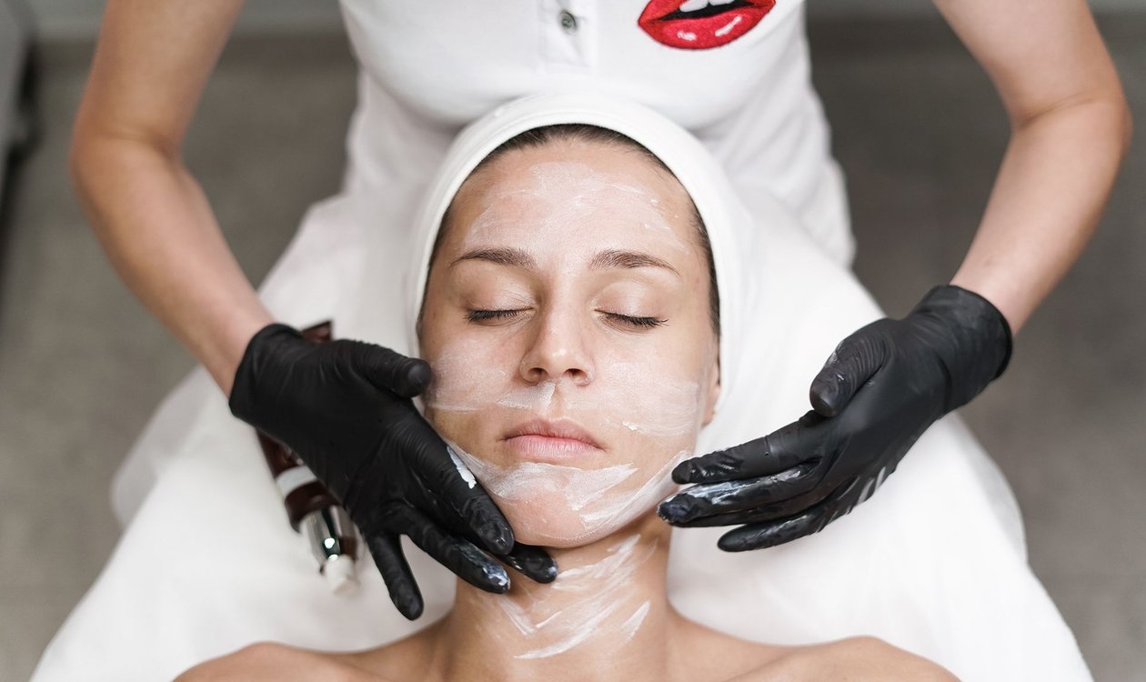 Woman relaxing while her face is gently cleansed during a facial treatment