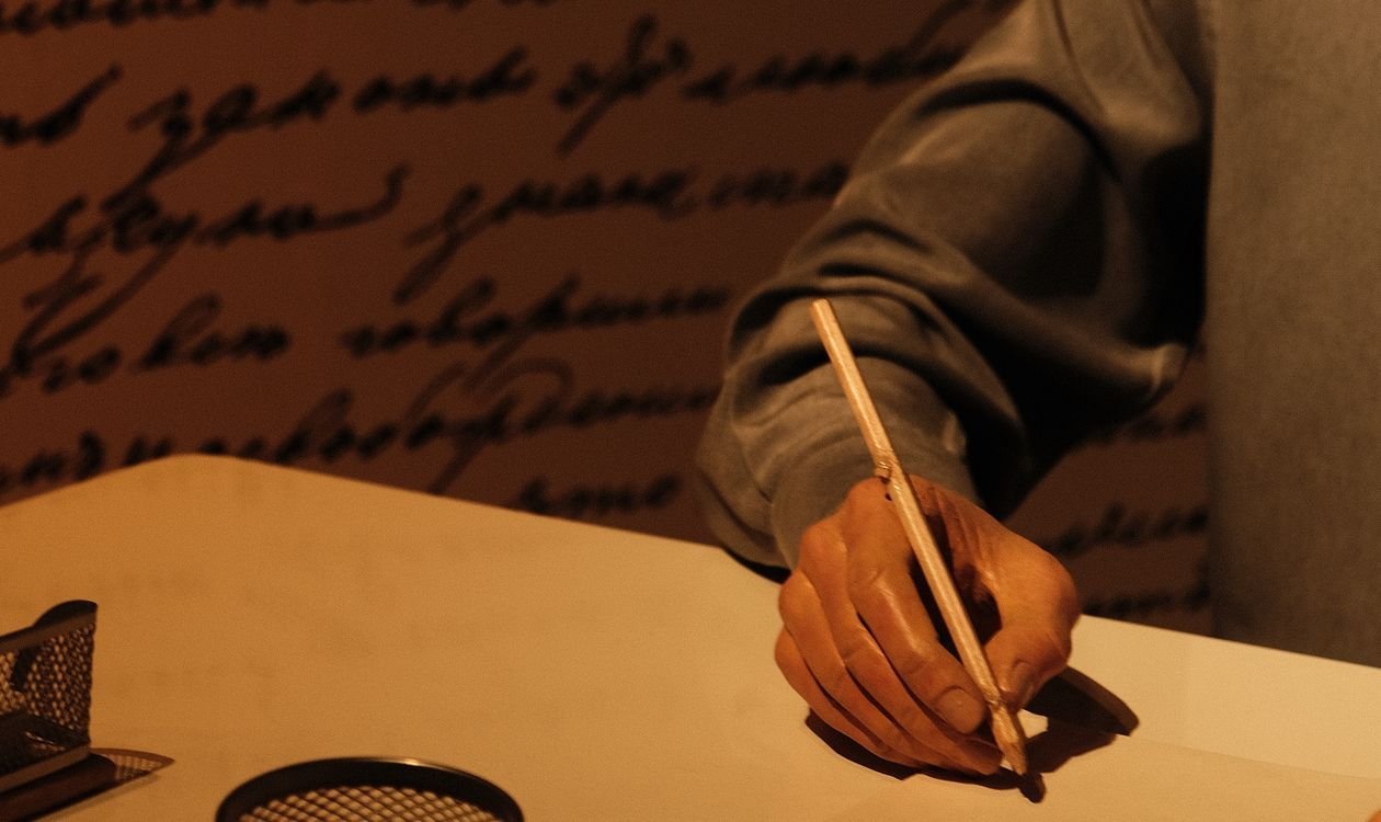 Person writing in a paper journal with a pen
